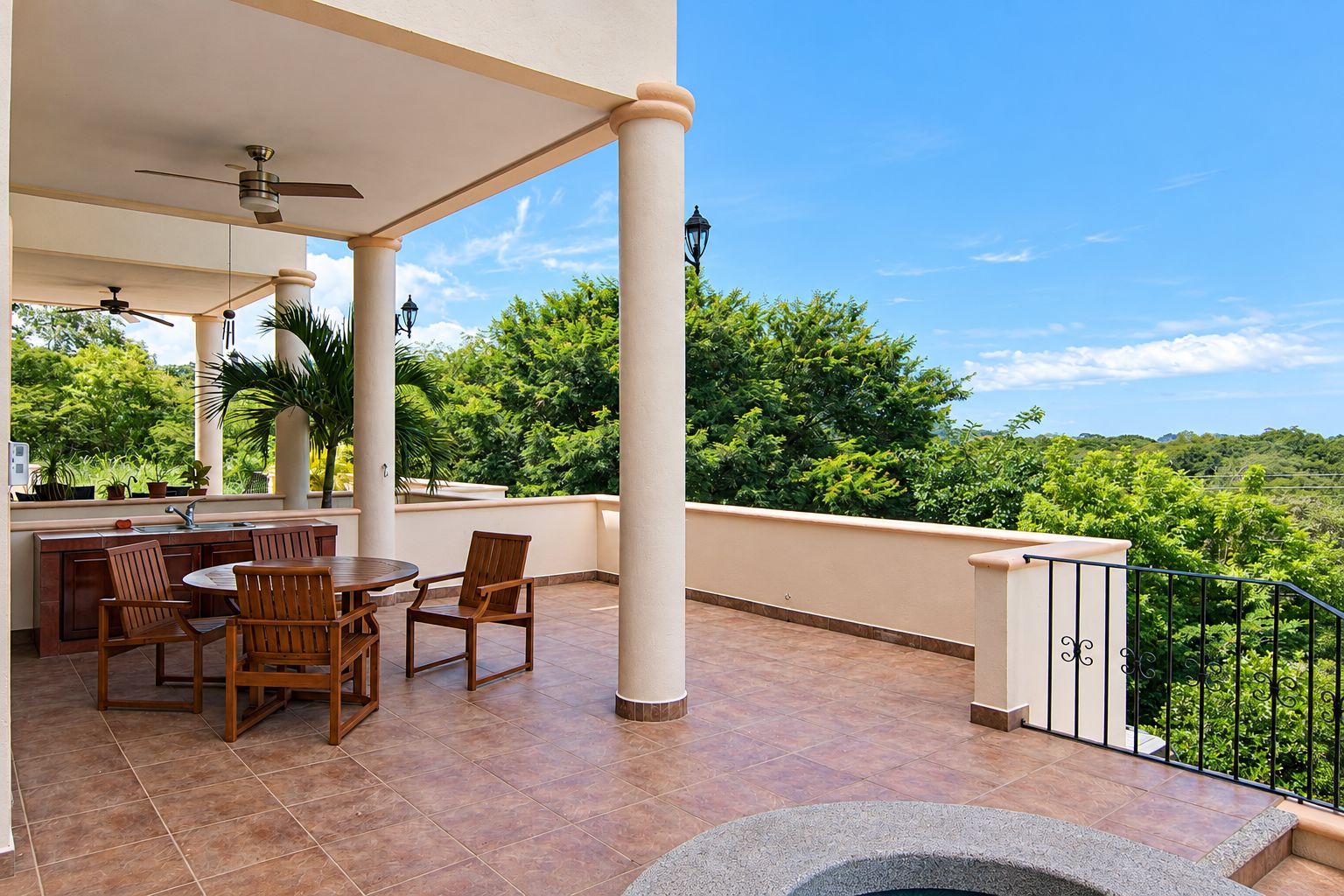 Eine überdachte Terrasse im Freien mit Essbereich, Spüle und Steinelement.