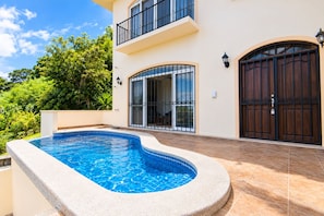 A residential property with a swimming pool, a two-story building, and a large wooden gate.