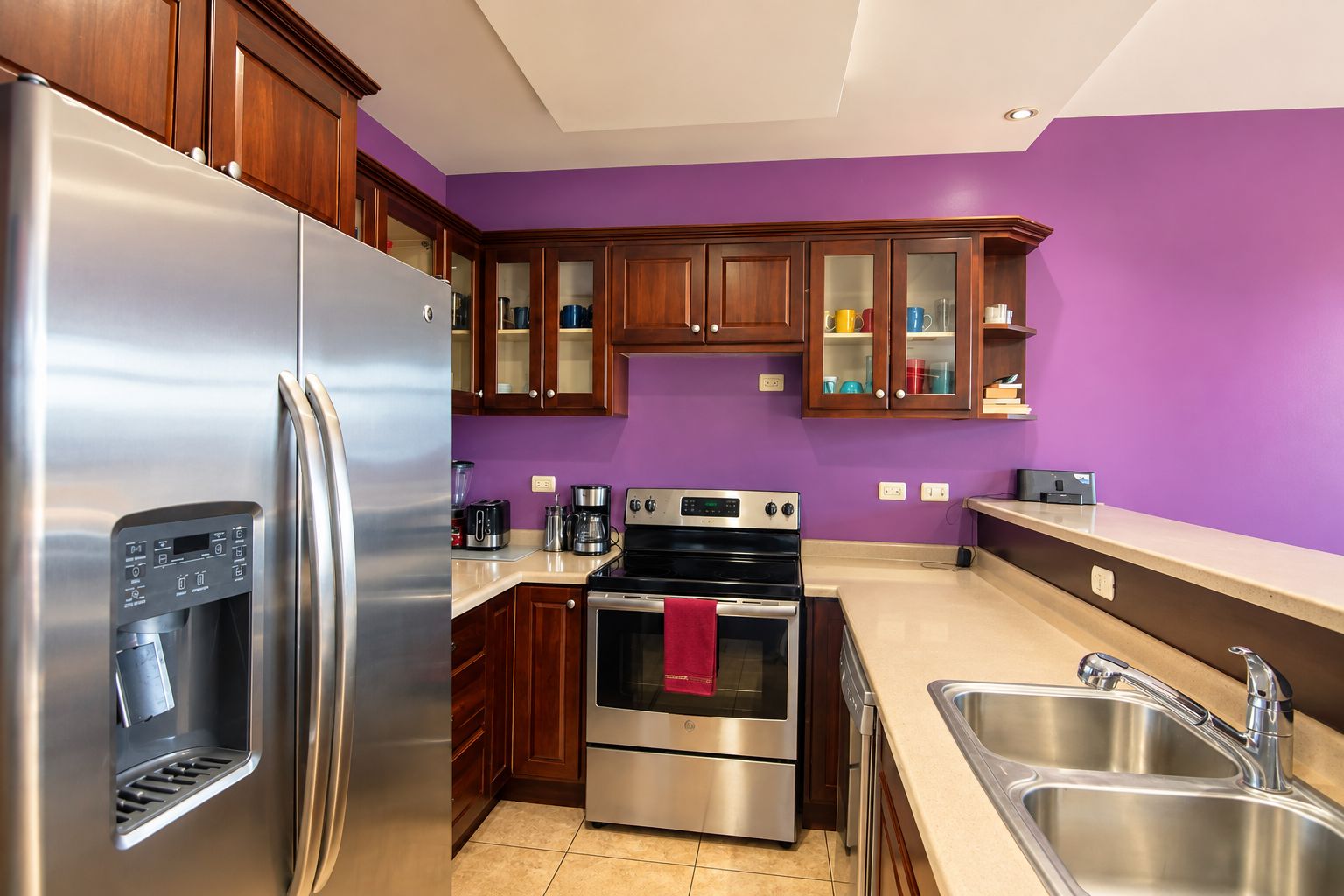 Une cuisine moderne dotée d’appareils électroménagers en acier inoxydable, de meubles en bois et d’un mur peint en violet.