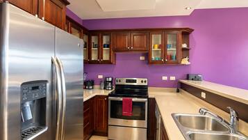 Une cuisine moderne dotée d’appareils électroménagers en acier inoxydable, de meubles en bois et d’un mur peint en violet.