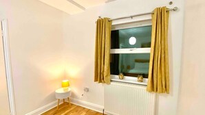 A room with a window, a radiator, and a small table with a lamp. - London apartment

 (London)