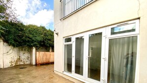 A building with large sliding glass doors, a concrete ground, and a wooden fence. - London apartment

 (London)
