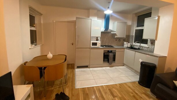 A compact kitchen with a dining table, microwave, oven, and a black trash bin. - London apartment

 (London)