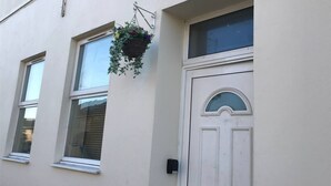 A building with a white door, windows, and a hanging flower basket. - London apartment

 (London)
