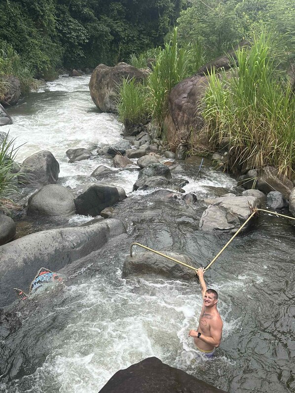 Una persona cruzando un río por un puente colgante.