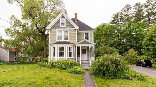 Ein zweistöckiges Haus mit Veranda und einem kleinen Garten.