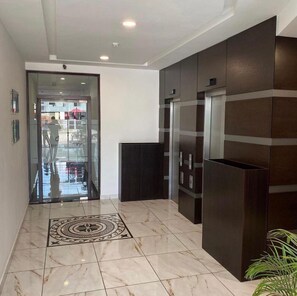 Experience the elegant lobby with a marble floor, dark paneling, and a welcoming reception area.
