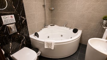 A bathroom with a large bathtub, toilet, and sink.