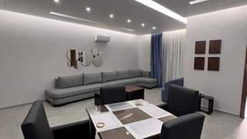 Ein modernes Wohnzimmer mit Essbereich, grauem Sofa und einem Couchtisch mit Papieren.