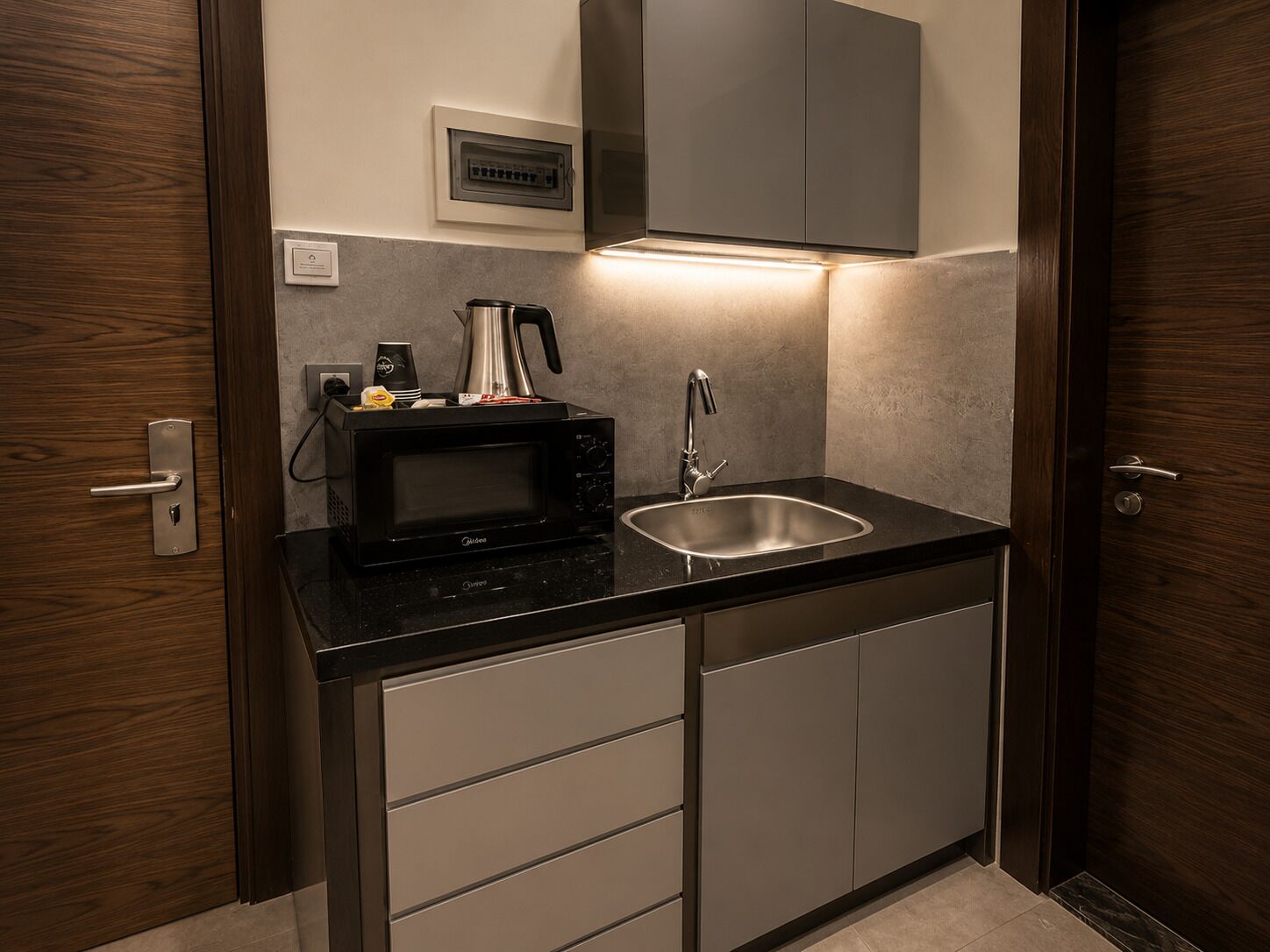 A compact kitchen with a microwave, coffee maker, and sink.