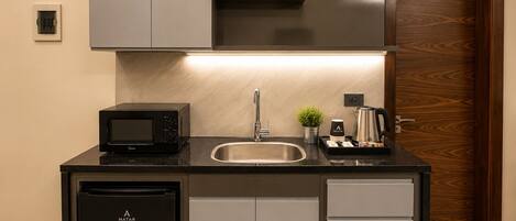 A compact kitchen with a built-in dishwasher, a microwave, a sink, and a coffee maker.