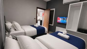 A hotel room with two beds, a TV, and an air conditioning unit.