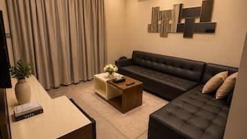 Una sala de estar con sofá, mesa de centro, televisor y decoración en la pared.