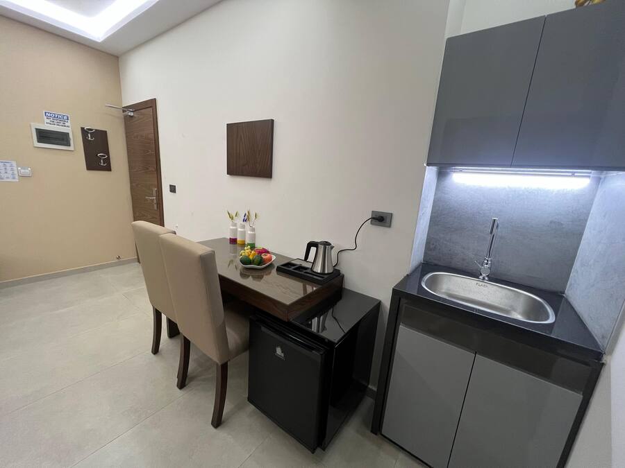 A compact kitchen with a sink, a small refrigerator, and a dining area with a chair and table.