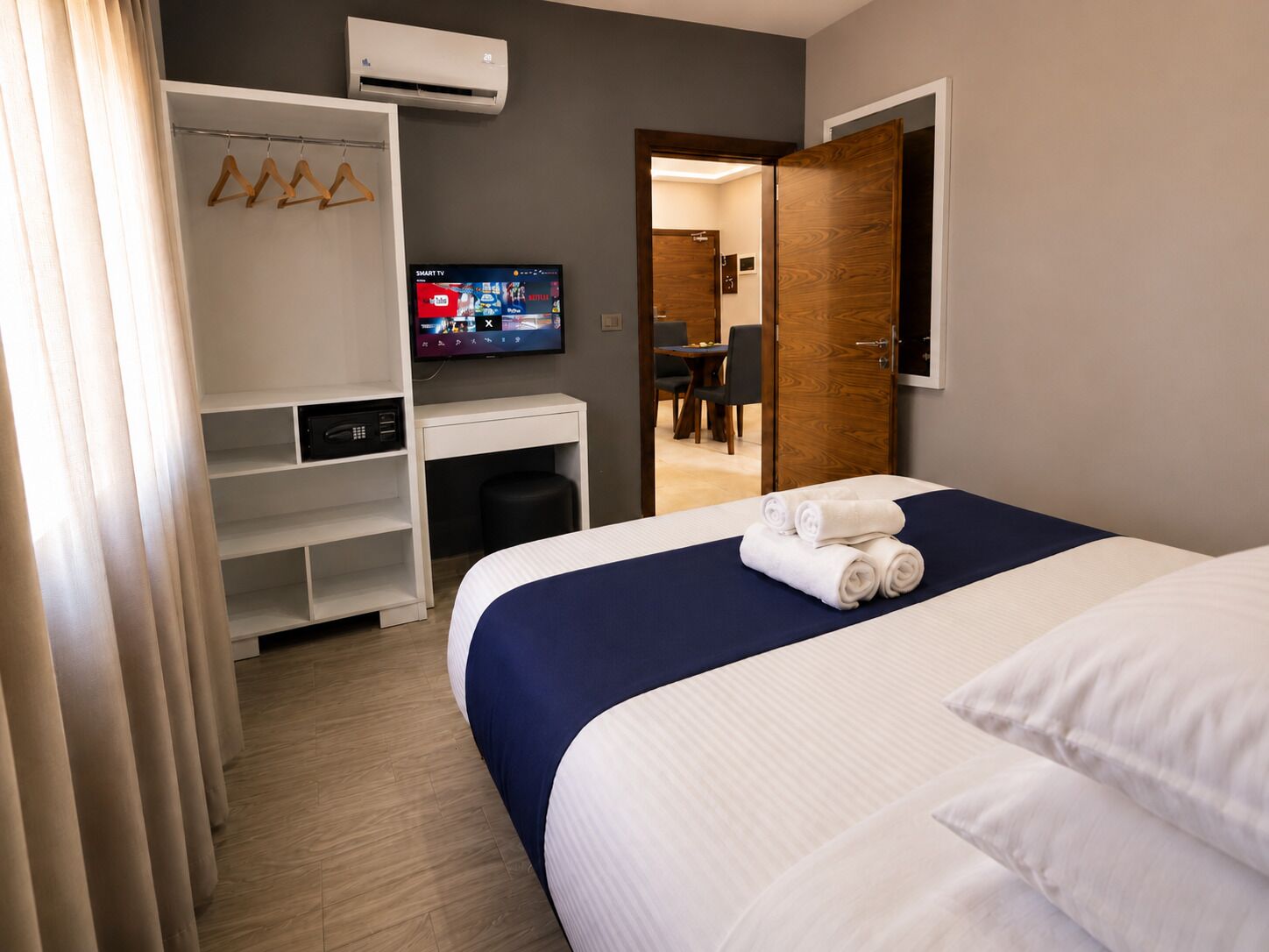 Habitación de hotel con cama, escritorio, televisor y armario.