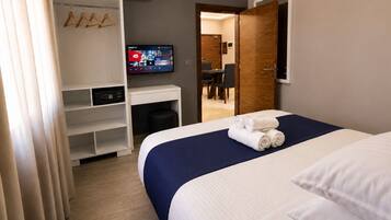 Habitación de hotel con cama, escritorio, televisor y armario.