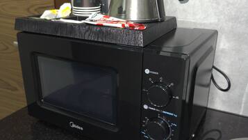A black microwave oven with a coffee pot on top, placed on a granite countertop.