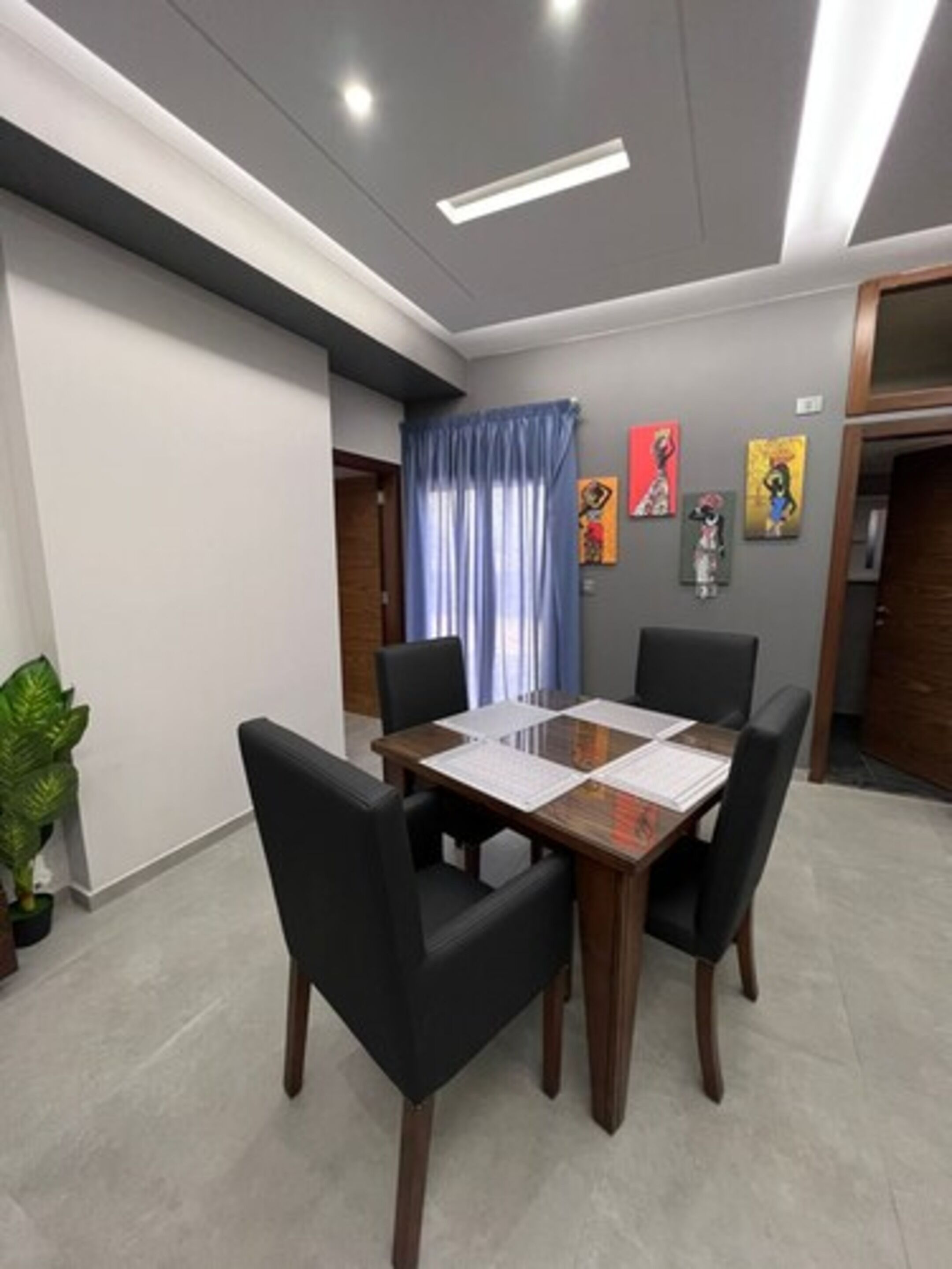 A conference room with a wooden table, four chairs, and a potted plant.