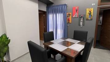 A conference room with a wooden table, four chairs, and a potted plant.