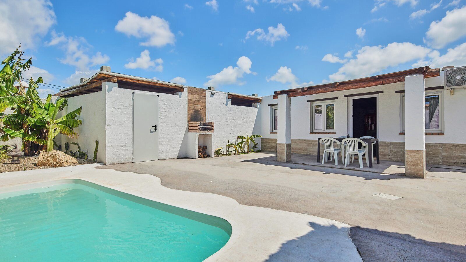 A two-story house with a swimming pool, outdoor seating, and a small garden.