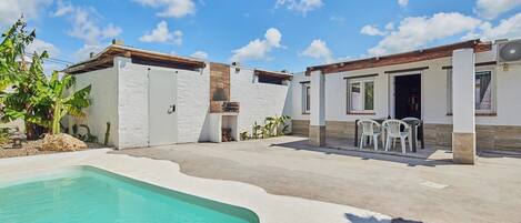 A two-story house with a swimming pool, outdoor seating, and a small garden.