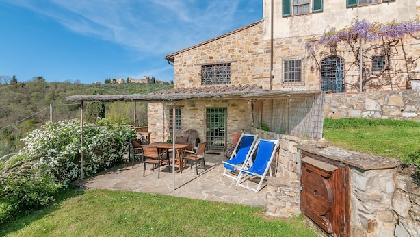 Un edificio de piedra con un patio, mobiliario exterior y vistas al campo.