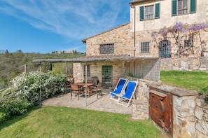 Un edificio in pietra con patio, posti a sedere all'aperto e vista sulla campagna.