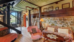 Una habitación acogedora con pared de piedra, una escalera de madera y un sofá estampado.