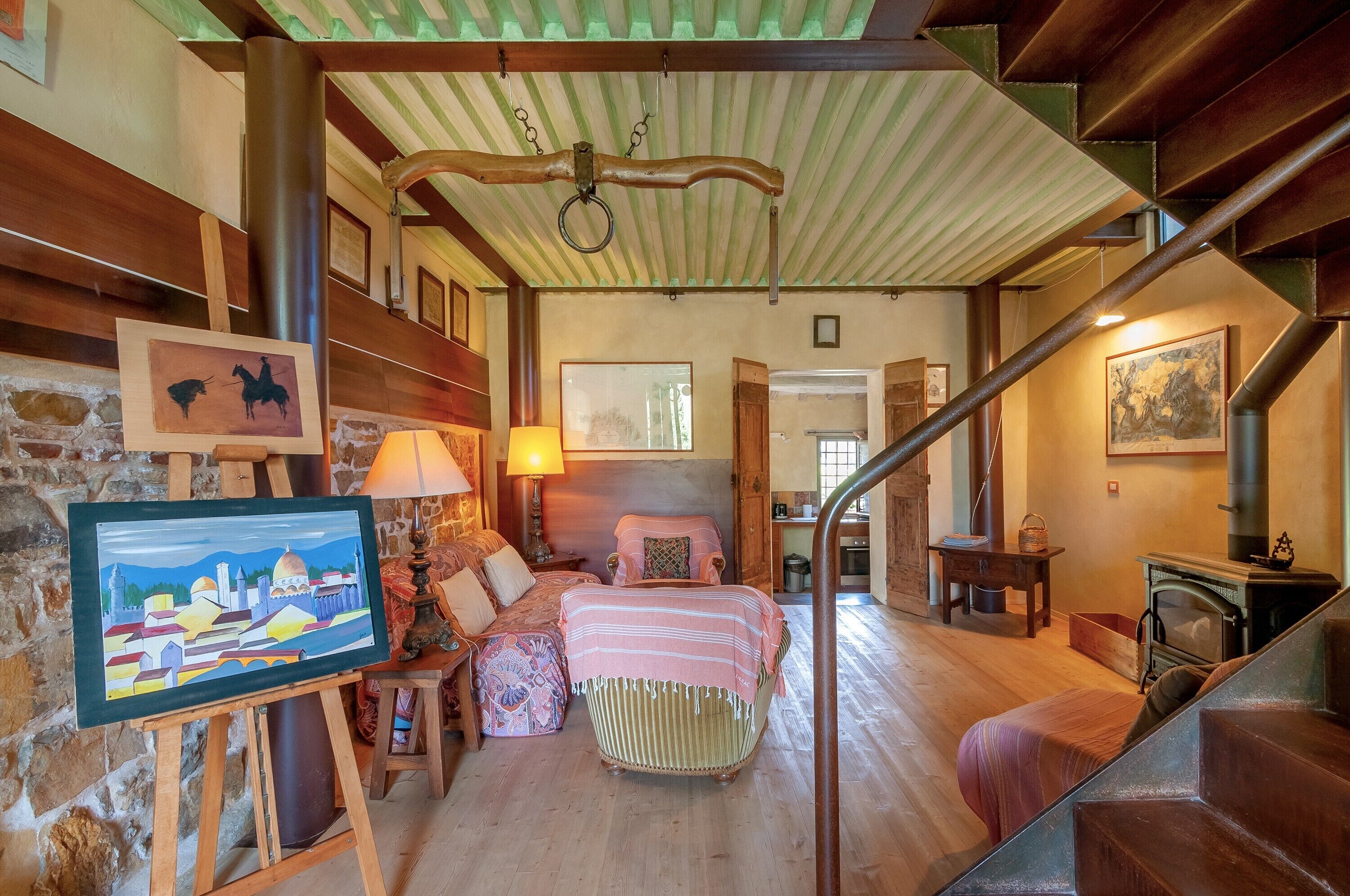 Une pièce confortable avec un lit, un tableau sur un chevalet, une cheminée et un escalier.