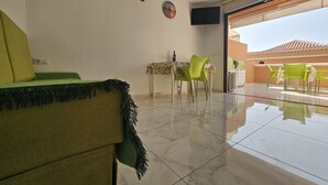 Un soggiorno moderno con un divano, un tavolo da pranzo con sedie e una TV a parete.