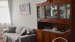 A living room with a sofa, a wooden cabinet with glass doors, and a painting on the wall. - Refuge for your family (Centro Guarapari)