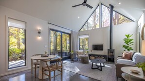 Un salon spacieux doté d’une cheminée, de grandes fenêtres et d’un ventilateur de plafond.