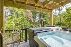 Ein Whirlpool auf einer Holzterrasse mit einer Hängematte, umgeben von Bäumen.