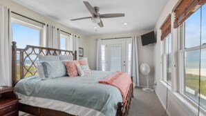 Quarto com cama grande, ventilador de teto e vista para o exterior.
