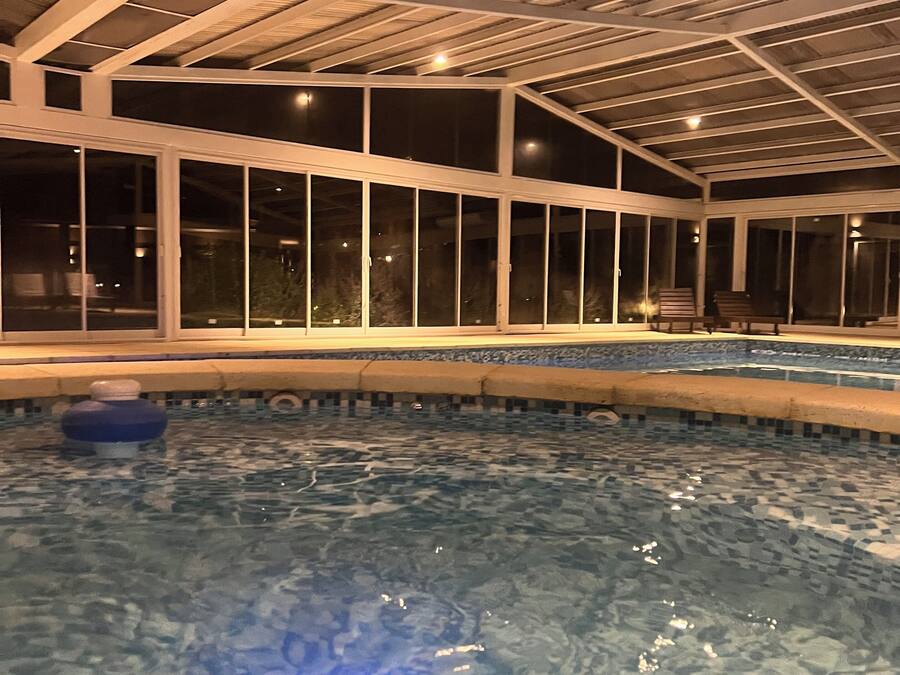 An indoor swimming pool with clear water, a blue light feature, and a ceiling with a grid pattern.