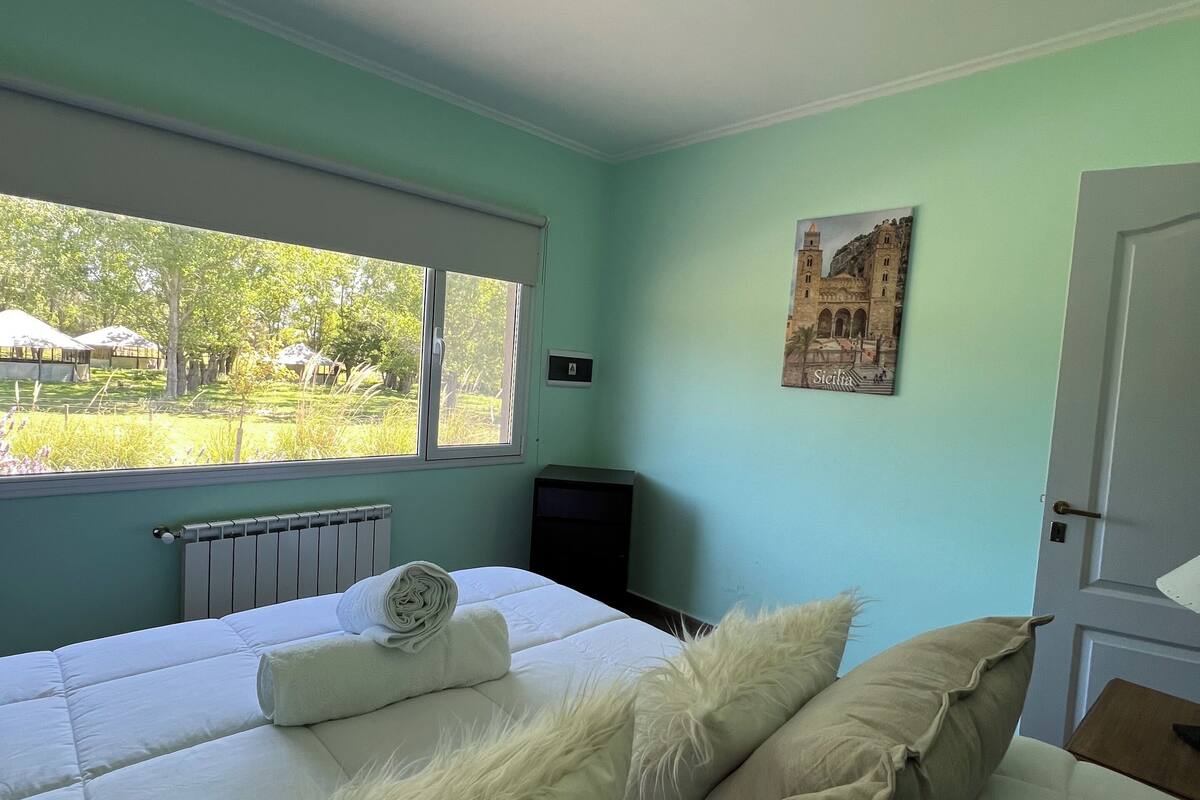 A bedroom with a bed, a radiator, a window, and a door.