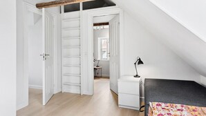 Ein Zimmer mit Schlafkoje, Schreibtisch mit Lampe und Regalelement.