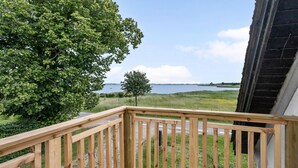 Eine Holterrasse mit Blick auf einen See und grüne Felder.