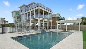 A multi-story house with a swimming pool, outdoor furniture, and a fenced patio area. - Breezeway: Luxury Listing- Largest Private Pool, mini-GOLF, Sunset  & Bay view (Galveston)