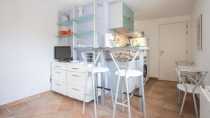 Cocina compacta con comedor, televisor y lavadora.