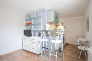Une cuisine compacte avec un coin repas, un téléviseur et un lave-linge.