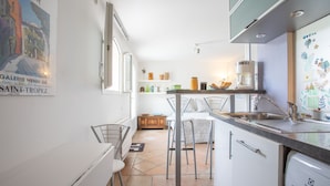 Cocina compacta con pileta, taburetes y refrigerador.