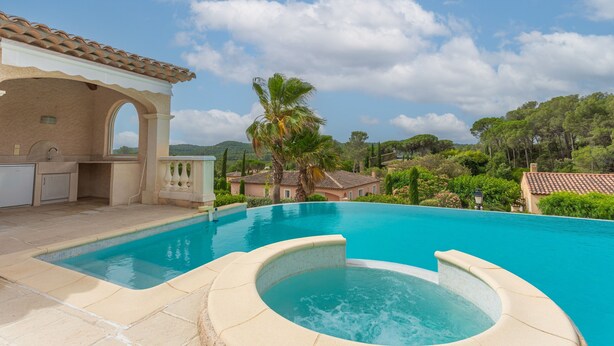 Una piscina con hidromasaje, cocina exterior y vistas del paisaje circundante.