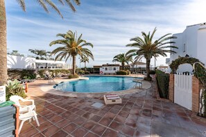 A swimming pool with palm trees, lounge chairs, and a white building in the background. - Apartment 'La Cala Mijas Playa Club' with Sea View, Wi-Fi and Air Conditioning (La Cala de Mijas)