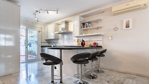 Moderni keittiö, jossa on baarituolit, ruostumattomasta teräksestä valmistettu liesituuletin ja sisäänrakennettu uuni.