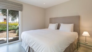 Una camera da letto con un letto grande, un comodino in vetro e vista attraverso una porta scorrevole.