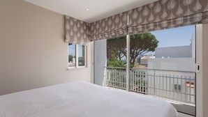 Una camera da letto con un letto grande, una finestra vista balcone e una tenda a motivi.