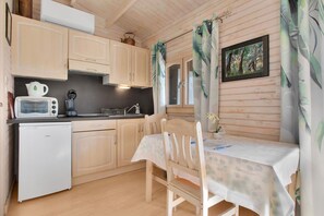A compact kitchen with wooden cabinets, a small refrigerator, a microwave, and a sink. - Chalet 'Superbe' with Private Terrace, Wi-Fi, and Air Conditioning (Roquebrune-sur-Argens)