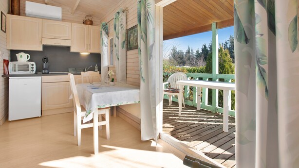 Interior de madera con cocina, comedor y vistas al exterior.