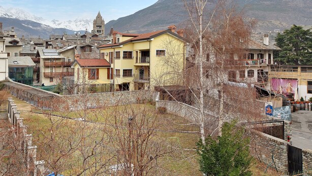 A town with traditional architecture, a church, and a mountain backdrop. - Apartment "Casa Mel" with Mountain View, Balcony & Wi-Fi (Aosta)